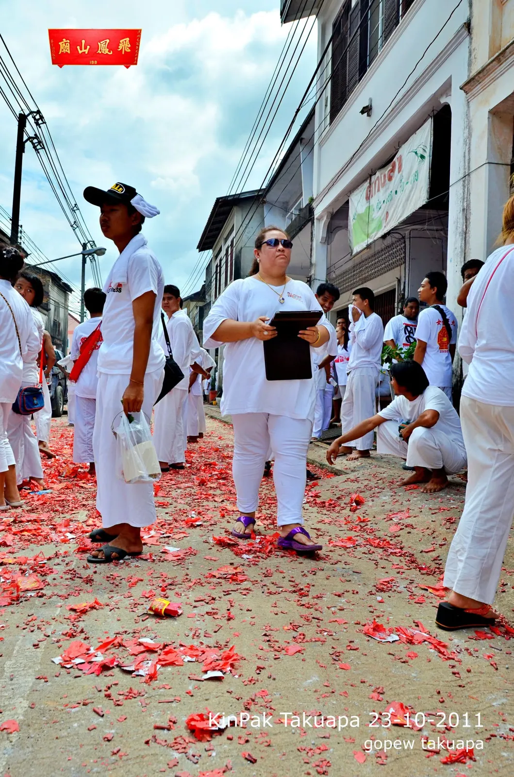 ถนนปูแดงด้วยเศษประทัด ผู้ร่วมงานยืนนั่งพักคุยกันหลังขบวนผ่าน